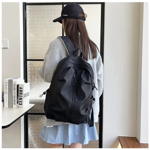 Rear view of model wearing a black large capacity nylon backpack with side pockets
