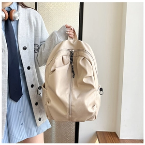Detail view of the beige nylon backpack with vertical zipper and drawstring side pockets