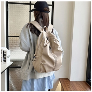 Detailed view of wide shoulder straps on a beige minimalist large capacity backpack