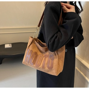 Close-up of brown suede tote bag featuring 3D HOOTO letters and metal chain strap