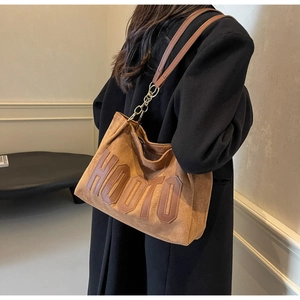 Brown suede tote bag with HOOTO applique detail and leather straps on model