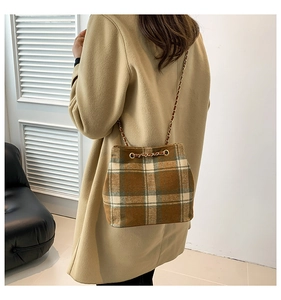Détail du sac seau en tweed à carreaux avec cordon de serrage et chaîne dorée