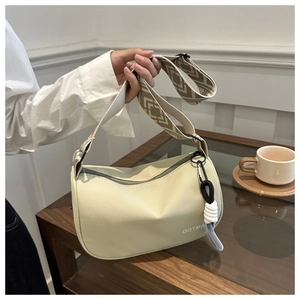 Close-up of OOTMAN cream canvas crescent bag with a wide geometric woven shoulder strap