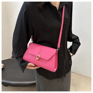 Détail macro d'un sac bandoulière rose fuchsia avec boucle dorée porté par un mannequin