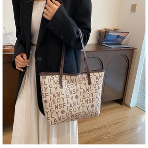 Lifestyle shot of large capacity beige tote bag with brown letter print and leather straps
