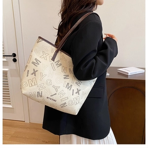 Detail of cream tote bag with dark brown leather trim and luxury letter print