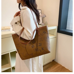 Detailed side view of brown tote bag with letter prints and slim shoulder strap