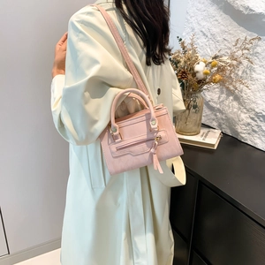 Pink leather shoulder bag with zipper fringe detail worn by a model in a modern room