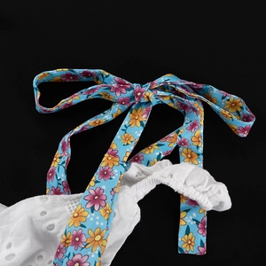 Detail van witte kant met een blauw lint met bloemenprint gestrikt in een mooie strik