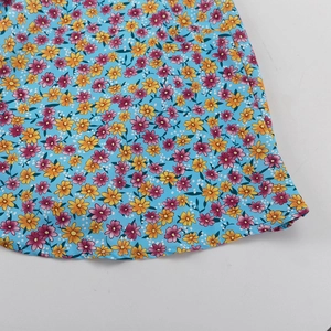 Detail van het ditsy bloemenpatroon op een lichtblauwe zomerjurk met gele en roze bloemen