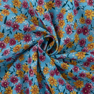 Detail van lichtblauwe chiffon stof met delicate gele en roze bloemenpatronen en textuur