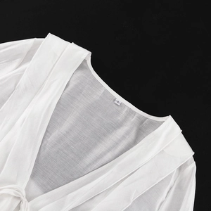 Détail de la texture en dentelle blanche transparente et col en V avec étiquette