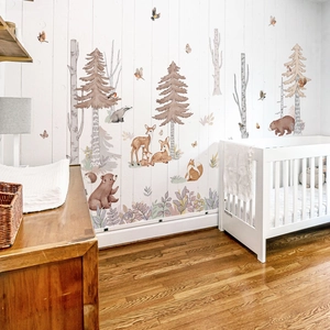 Nursery wall stickers featuring forest animals and trees in a cozy baby room scene