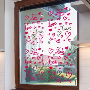Detail of red Love heart static window clings on kitchen glass with garden view background