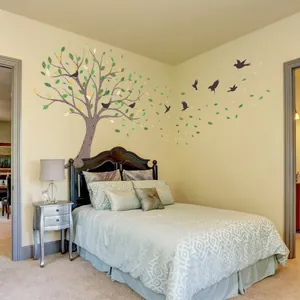 Artistic tree wall decal with colorful leaves and bird silhouettes in a bedroom setup