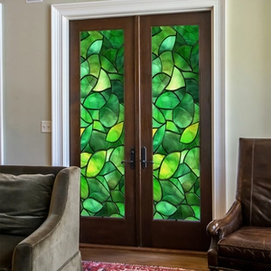 Detail of green leaf stained glass window film on dark brown double wooden doors