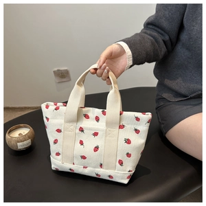 Detail of strawberry print on cream corduroy mini handbag with sturdy ribbon handles