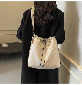 Detail van crème nylon emmertas met dubbele voorzakken en verstelbare riem op model getoond