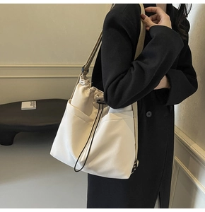 Detail van verstelbare riem en trekkoordsluiting op minimalistische beige nylon emmertas