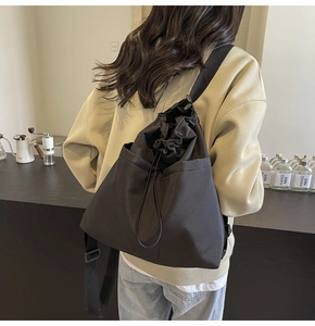 Achteraanzicht van model met een minimalistische zwarte tote bag met trekkoordsluiting