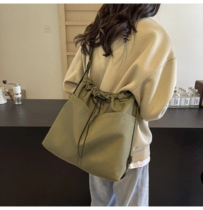 Detail van olijfgroene nylon draagtas met trekkoordsluiting en zijvakken op de tas