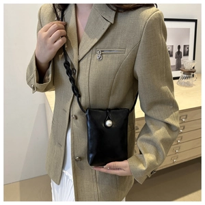 Détail d'un petit sac bandoulière noir en cuir avec fermoir perle et bandoulière tressée
