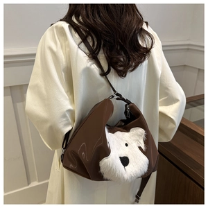 Detail of the brown crossbody bag featuring a cute white plush puppy design on the back