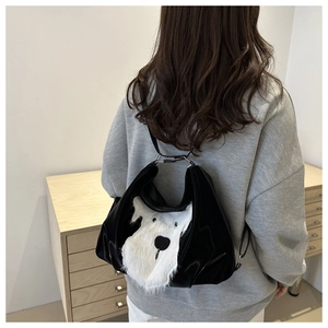 Detail shot of a black patent leather tote bag with a plush dog design on model shoulder