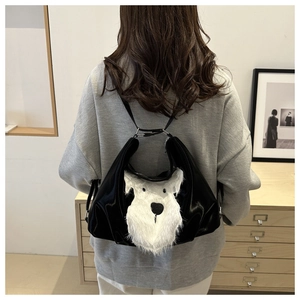Detail of cute white plush dog motif on a glossy black leather shoulder tote bag