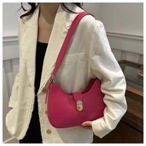 Close-up of fuchsia shoulder bag with gold twist lock on a white textured blazer