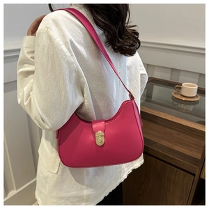 Detail view of pink semi-circle faux leather bag with gold buckle on a model in white blazer