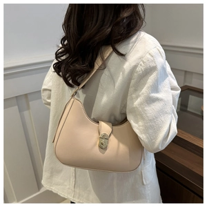 Close-up of beige hobo shoulder bag with gold metal buckle worn by a model