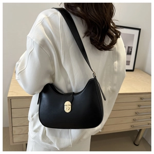 Close-up of a black leather half-moon underarm bag with a golden clasp on a model