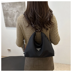 Detail shot of a black nylon crescent shoulder bag with silver chain and metal logo