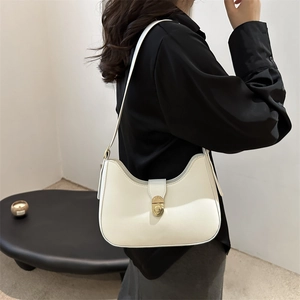 Minimalist beige shoulder bag with gold twist lock shown on model in urban style