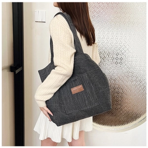 Detailed close-up of a large grey tote bag with front pocket and textured fabric finish