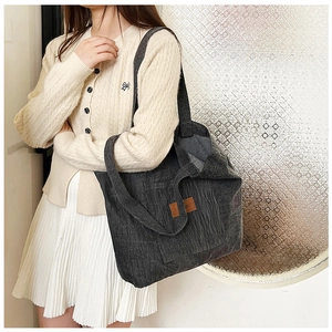 Detail of grey corduroy tote bag showing thick ribbed texture and retro leather patch