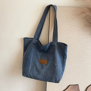 Minimalist blue denim tote bag with brown leather label and shoulder straps