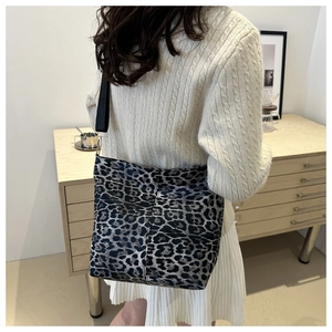 Detail showing leopard print canvas bag texture with wide black nylon shoulder strap