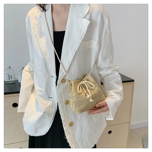 Detail of beige straw bucket bag featuring wavy weave pattern and cotton drawstring closure