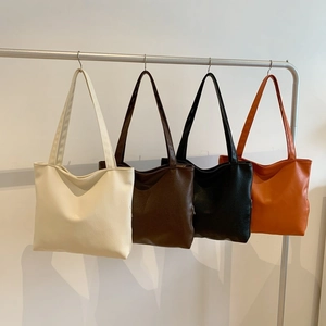 Minimalist PU leather shoulder bags in four colors displayed on a sleek metal stand