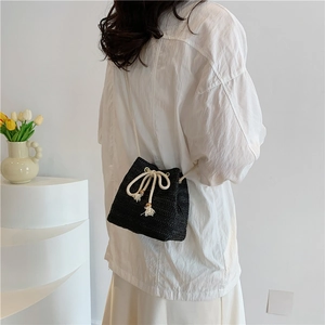 Fashionable black straw woven bucket bag with drawstring closure and crossbody strap