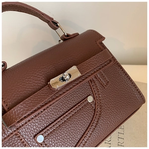 Detailed macro view of brown lychee grain leather texture and silver buckle on Kelly bag