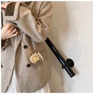 Golden seashell mini crossbody bag shown on model with metallic shell texture and chain
