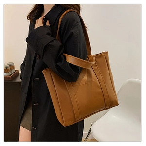 Chic caramel brown tote bag in matte PU leather shown in a stylish lifestyle setting