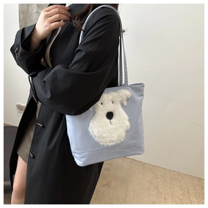 Détail du cabas bleu clair avec application de chien en peluche et texture en nylon lisse