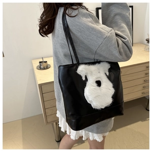 Détail d'un grand sac cabas noir avec un motif de chien Schnauzer en peluche et anses en cuir
