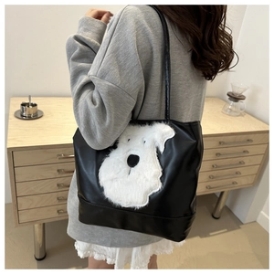 Détail du sac cabas en similicuir noir avec broderie appliquée d'un chiot en peluche blanc