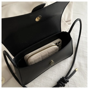 Detail view of the black minimalist bag showing interior capacity and magnetic snap closure