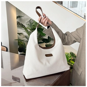 Close-up of white corduroy texture and brown leather strap on a hobo shoulder bag